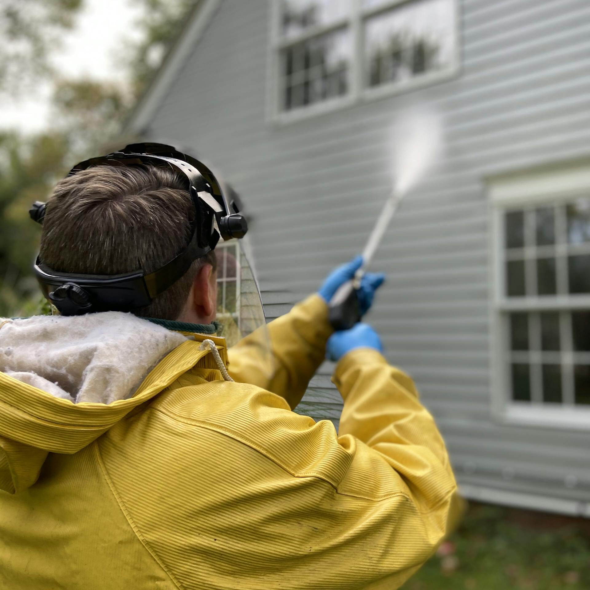 Back View of a Person Pressure Washing a House